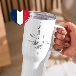 May include: White travel mug with a handle, featuring a design of connected hands and the names "Hugo", "Alex", "Lucie", and "Sacha". The mug also has the text "Grand-M&egrave;re" and a clear lid. A French flag heart is on the left.