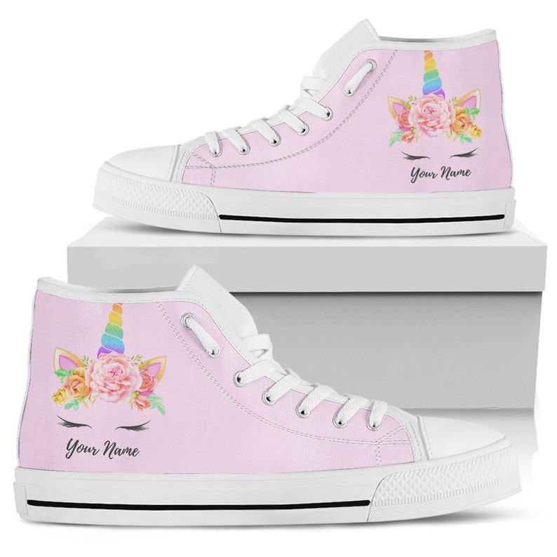 May include: Pink high-top canvas shoes with a unicorn design featuring a rainbow horn, flowers, and eyelashes. The shoes have white laces and a white sole. The text "Your Name" is printed on the shoes.
