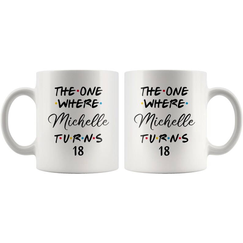 May include: Two white coffee mugs with black text that reads "The One Where Michelle Turns 18". The text is decorated with colorful dots.