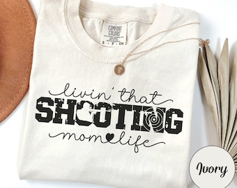May include: Ivory t-shirt with the text "Livin' that SHOOTING mom life" in black with a target graphic.