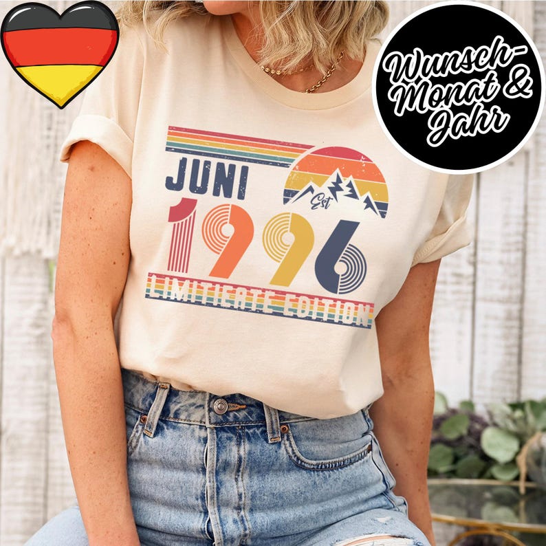 May include: Cream-colored t-shirt with a retro design featuring the word "JUNI" above the numbers "1996" in a rainbow color scheme. The shirt also includes the text "LIMITED EDITION" and a mountain graphic.
