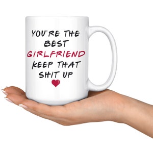 May include: White ceramic coffee mug with black text that reads "You're the best girlfriend keep that sh*t up" with a red heart.