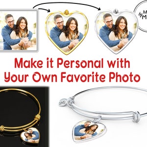 May include: A gold and silver bangle bracelet with a heart-shaped charm that can be personalized with a photo. The charm features a couple in a loving embrace. The bracelet is made by Made by Moms.