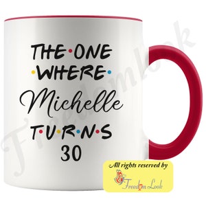 May include: White ceramic mug with a red rim and handle. The mug has black text that reads "THE ONE WHERE Michelle TURNS 30". The text has colorful dots between the words.