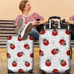May include: Two white luggage covers with a repeating pattern of red ladybugs and black outlines of flowers on a white background.