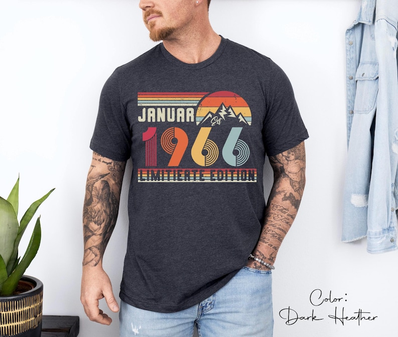 May include: Dark heather gray t-shirt with a retro design. The graphic includes the text "JANUARY 1966" with a mountain and sunset illustration. The words "LIMITIERTE EDITION" are also printed on the shirt.
