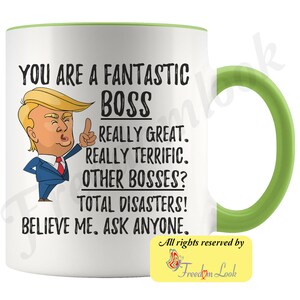 May include: White ceramic coffee mug with a green rim and handle. The mug features a cartoon image of Donald Trump with the text "You are a fantastic boss. Really great. Really terrific. Other bosses? Total disasters! Believe me. Ask anyone."  The text "All rights reserved by Freedom Look" is printed on the bottom of the mug.