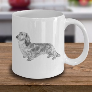 Puede incluir: Taza de caf&eacute; de cer&aacute;mica blanca con una ilustraci&oacute;n en blanco y negro de un perro salchicha.