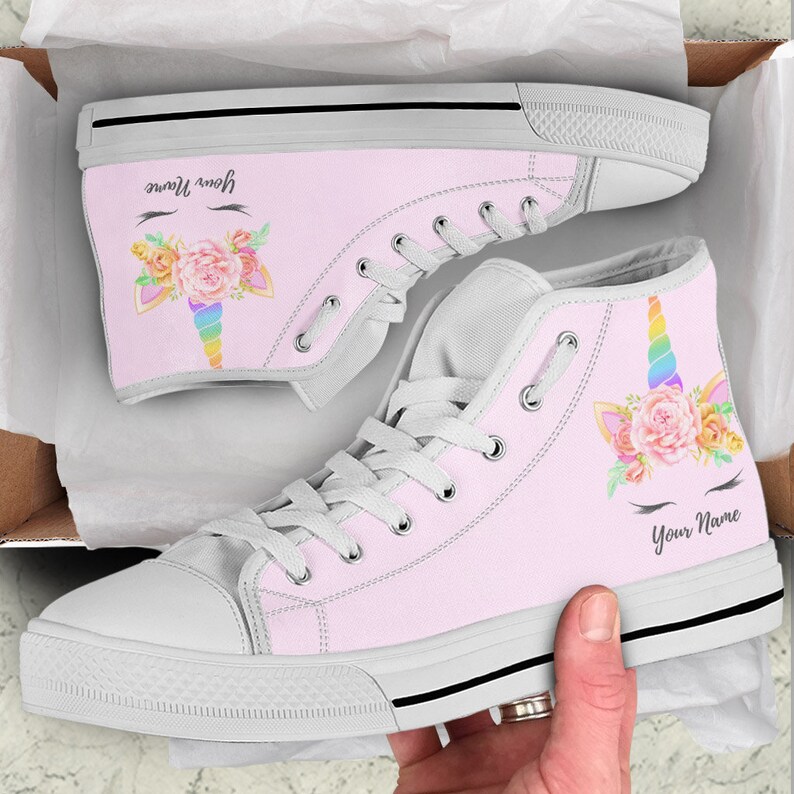 May include: Pink high-top canvas shoes with a unicorn design. The unicorn has a rainbow horn, pink flowers, and eyelashes. The shoes say "Your Name" on the side.