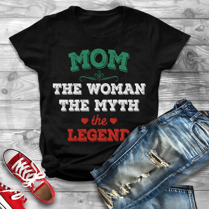 Puede incluir: Camiseta negra con texto blanco que dice "MOM THE WOMAN THE MYTH the LEGEND" con corazones rojos alrededor de la palabra "the".