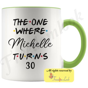 May include: White ceramic mug with a green rim and handle. The mug has black text that reads "THE ONE WHERE Michelle TURNS 30" with colorful dots between the words.