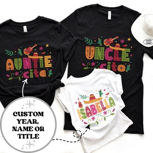 May include: Three black t-shirts with colorful designs and text. The shirts say "Auntie Cita", "Uncle Cito", and "Isabella".