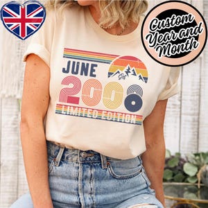 May include: Cream-colored t-shirt with a retro design featuring the text "JUNE 2008 LIMITED EDITION". The design includes a rainbow-colored arc, a mountain graphic, and a circular design. A heart-shaped Union Jack flag is in the upper left corner.