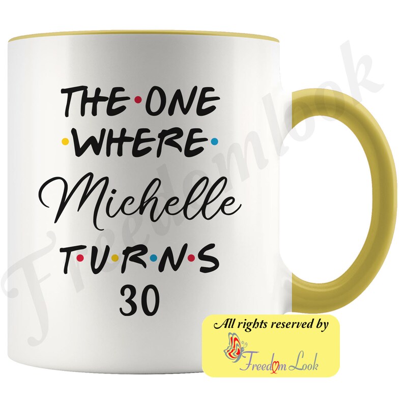 May include: White ceramic mug with a yellow rim and handle. The mug features black text that reads "THE ONE WHERE Michelle TURNS 30" with colorful dots between the words.