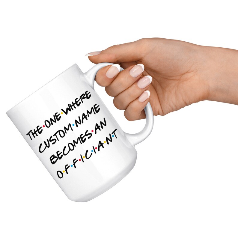 K&ouml;nnte beinhalten: Eine wei&szlig;e Keramiktasse mit einer schwarz-wei&szlig;en Grafik, auf der "The One Where Custom Name Becomes An Officiant" steht.