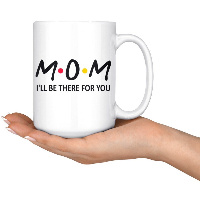 May include: White ceramic coffee mug with a black graphic that says "M.O.M. I'll be there for you".