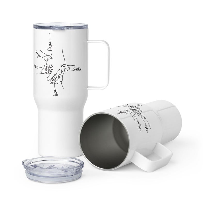 May include: White travel mug with a handle and a clear lid. The mug features a black line drawing of hands and the names "Hugo", "Alex", "Lucie", "Sacha", and "Papa". The second mug is lying on its side.