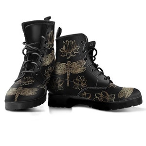 Puede incluir: Botas de cuero negro con un patrón de libélula y flor de loto dorada.