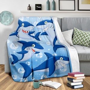 May include: A blue fleece throw blanket with a cartoon design of four sharks swimming in a blue ocean with white bubbles.