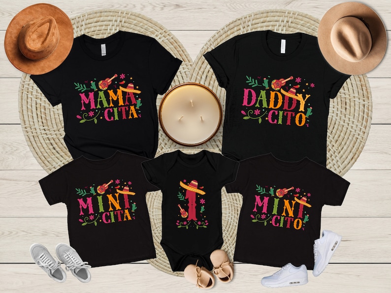 May include: A set of four black t-shirts with a festive Mexican theme. The shirts feature the text "Mama Cita", "Daddy Cito", and "Mini Cito" with a guitar, sombrero, and floral design.