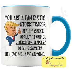 Op de afbeelding: Een witte keramische koffiemok met een blauwe rand en handvat. De mok heeft een cartoonafbeelding van Donald Trump met de tekst "You are a fantastic stock trader. Really great. Really terrific. Other stock traders? Total disasters! Believe me. Ask anyone."