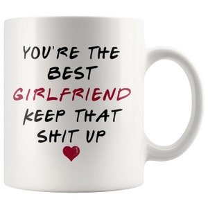 May include: White ceramic coffee mug with black text that reads "You're the best girlfriend keep that sh*t up" with a red heart.