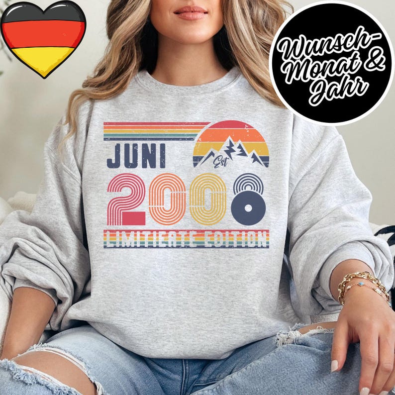 K&ouml;nnte beinhalten: Hellgraues Sweatshirt mit Retro-Design. Das Design umfasst den Text "JUNI 2008" in Rot, Gelb und Blau, eine Berg-Grafik und die Worte "LIMITED EDITION". Ein Herz mit der deutschen Flagge befindet sich in der oberen linken Ecke.