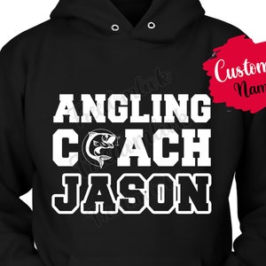 May include: Black hooded sweatshirt with white text that reads "Angling Coach" and a fish graphic. The text "Jason" is also printed in white below the main text. The text "Custom Name" is written in red on a white background in the upper right corner of the image.