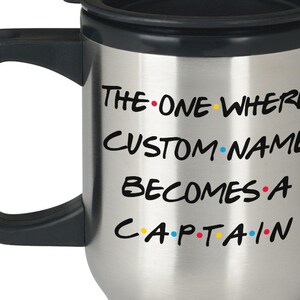 May include: Stainless steel travel mug with a black lid and handle. The mug has a white inscription that reads "The One Where CUSTOM NAME Becomes A Captain" with colourful dots between each word.