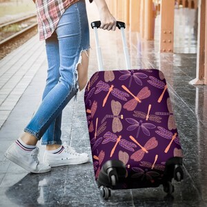 May include: Purple suitcase with a dragonfly pattern. The dragonfly design is in shades of orange and white.