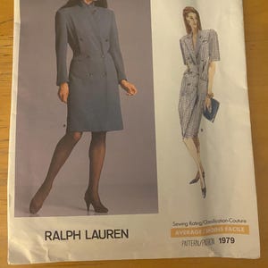 May include: A vintage Vogue Patterns sewing pattern featuring designs by Ralph Lauren. The cover shows a woman in a double-breasted dress and a second design. The text reads "AMERICAN DESIGNER" and "PATTERN/PATRON 1979".
