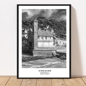 May include: Monochrome print of Kingsand, Cornwall, showing a clock tower and coastal buildings. The print includes the text "Kingsand Cornwall" and coordinates 50.3334° N, 4.2016° W.