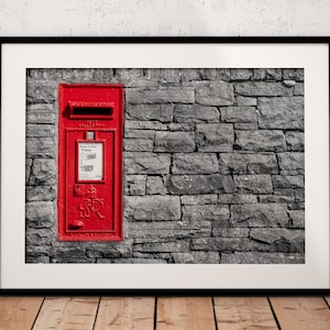 Könnte beinhalten: Gerahmter Druck eines leuchtend roten britischen Briefkastens in einer grauen Steinmauer. Der Briefkasten hat einen Schlitz für Post und einen Abholplan. Der Druck ist schwarz gerahmt und auf weißem Hintergrund montiert.