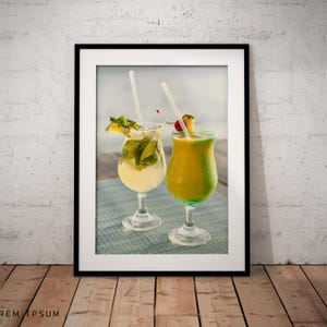 Può includere: Stampa incorniciata con due cocktail tropicali. Uno è una bevanda di colore chiaro con menta e una fetta di limone, l'altro è una bevanda gialla guarnita con una ciliegia e ananas. Entrambi hanno cannucce.