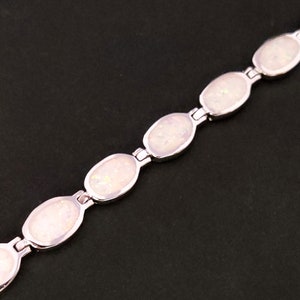 Puede incluir: Un brazalete de plata con piedras de &oacute;palo blanco de forma ovalada. El brazalete est&aacute; hecho de una cadena de plata con un cierre.
