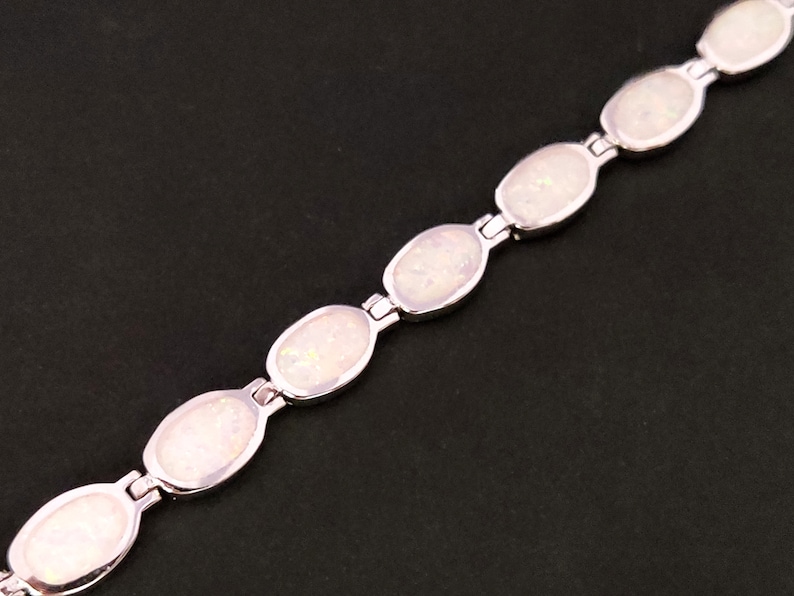 Puede incluir: Un brazalete de plata con piedras de &oacute;palo blanco de forma ovalada. El brazalete est&aacute; hecho de una cadena de plata con un cierre.