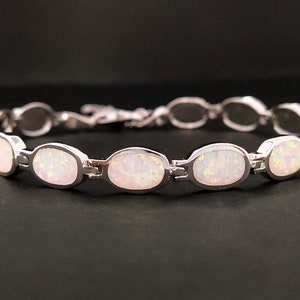Puede incluir: Una pulsera de plata con piedras de &oacute;palo blanco de forma ovalada. La pulsera tiene un cierre de broche.