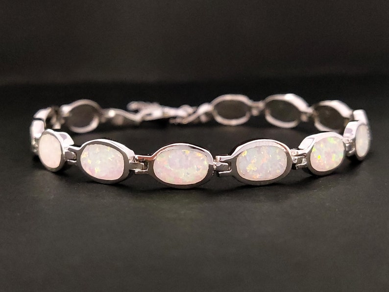 Puede incluir: Una pulsera de plata con piedras de &oacute;palo blanco de forma ovalada. La pulsera tiene un cierre de broche.