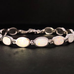 Puede incluir: Una pulsera de plata con piedras de &oacute;palo blanco de forma ovalada.
