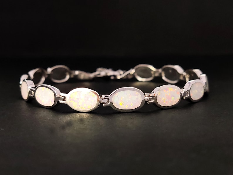 Puede incluir: Una pulsera de plata con piedras de &oacute;palo blanco de forma ovalada.