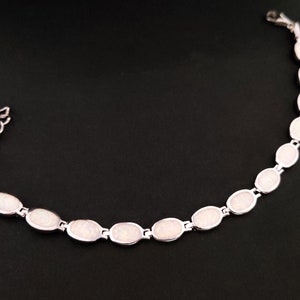 Puede incluir: Un brazalete de plata con piedras de &oacute;palo blanco de forma ovalada.