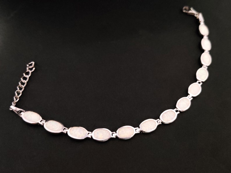 Puede incluir: Un brazalete de plata con piedras de &oacute;palo blanco de forma ovalada.