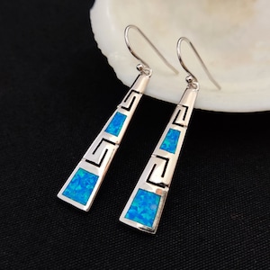 Può includere: Un paio di orecchini pendenti in argento con pietre di opale blu e un design a chiave greca.