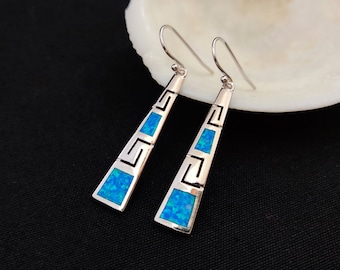 May include: A pair of silver dangle earrings with blue opal stones and a Greek key design.