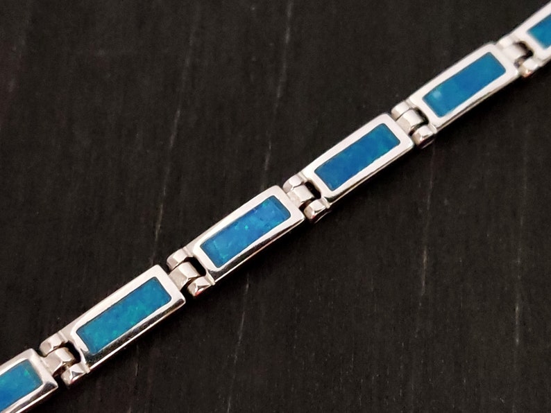 Puede incluir: Un brazalete de plata con piedras rectangulares de &oacute;palo azul. El brazalete tiene un dise&ntilde;o de eslabones.