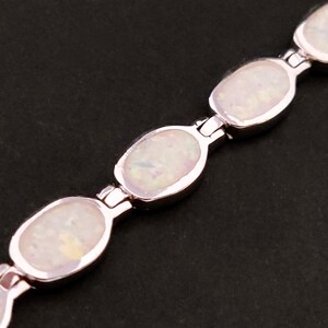 Puede incluir: Un brazalete de plata con piedras de &oacute;palo blanco de forma ovalada. El brazalete est&aacute; hecho de secciones enlazadas con un cierre de plata.