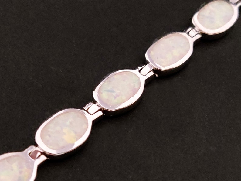 Puede incluir: Un brazalete de plata con piedras de &oacute;palo blanco de forma ovalada. El brazalete est&aacute; hecho de secciones enlazadas con un cierre de plata.