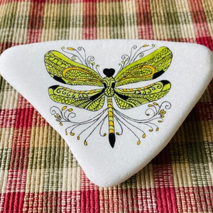 K&ouml;nnte beinhalten: Ein wei&szlig; bemalter Stein mit einem gelben und schwarzen Libellen-Design. Die Libelle hat komplizierte Details und ist im Doodle-Stil bemalt.