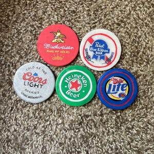 Puede incluir: Cinco posavasos redondos y coloridos con diferentes logotipos de marcas de cerveza. Los posavasos est&aacute;n hechos de un material duro y duradero y presentan los logotipos de Budweiser, Pabst Blue Ribbon, Coors Light, Heineken y Miller Lite.