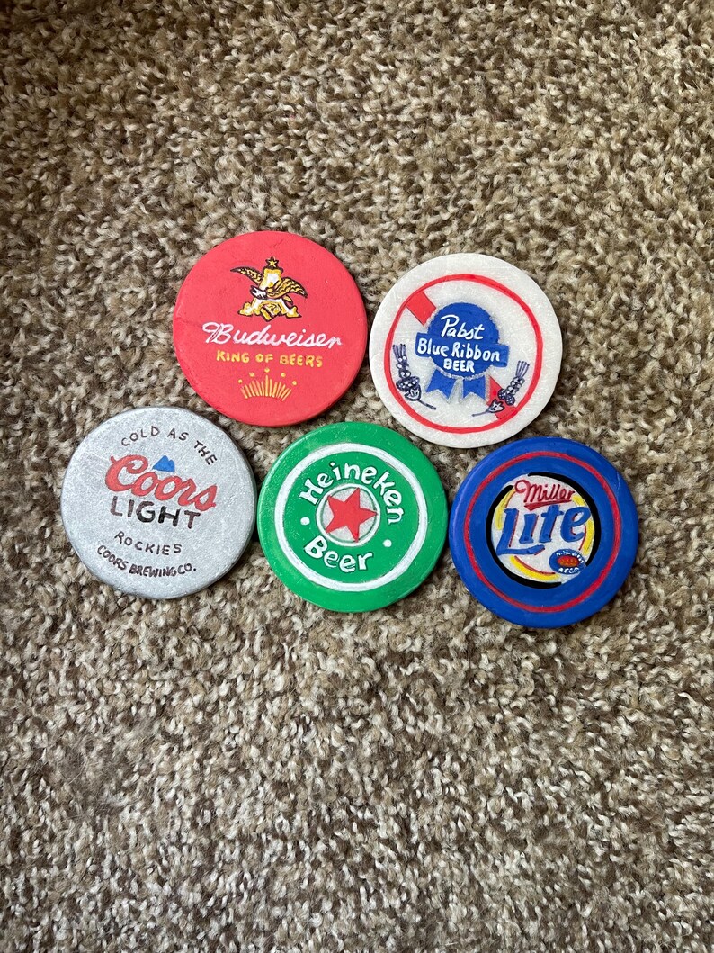 Puede incluir: Cinco posavasos redondos y coloridos con diferentes logotipos de marcas de cerveza. Los posavasos est&aacute;n hechos de un material duro y duradero y presentan los logotipos de Budweiser, Pabst Blue Ribbon, Coors Light, Heineken y Miller Lite.